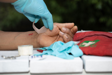 Safe workplace first aider wearing a blue safety glove when applying first aid plaster bandage on...