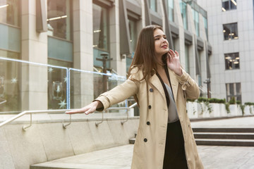 stylish young businesswoman wearing smart outfit catching taxi in the middle of the street, looking gorgeous, style and beauty concept