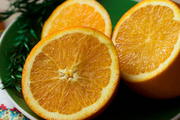 Oranges cut into slices lie on a green plateм