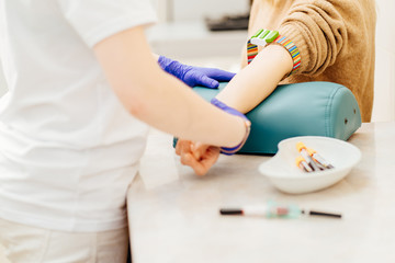Close up of nurse disinfecting male arm before blood test. Man is sitting on chair near medical set