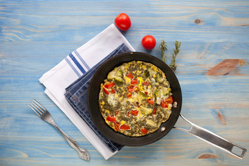 Frittata with broccoli, sweet peppers, tomatoes and herbs in skillet. Italian style omelette with vegetables