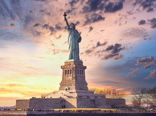 famous statue of  liberty and dramatic sky at sunset with orange colors