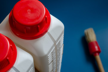 Two white plastic bottles and a paint brush. Top view of a pair of bottles with red caps. Home...