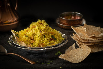 Indian almond pilaf with papad against a dark backround