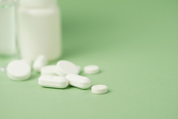 White medical pills and medical preparations in with bottles, glass ampoues,close-up on green background. Closeup photo of medical preparations with copy spaes.