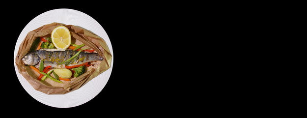 Grilled seabass with vegetables and lemon, served on paper.Isolated on a black background.Panorama for banners.Copy spase