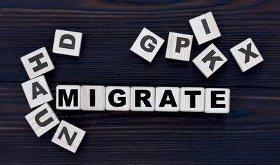 concept of the word migrate on cubes on a dark wooden background