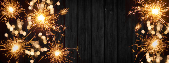 Silvester background banner panorama long- sparklers and bokeh lights on rustic wooden texture,...