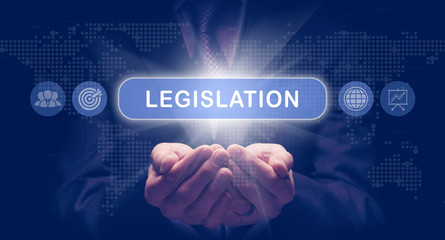 Businessmans cupped hands holding an Legislation business concept on a computerised display.
