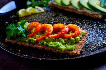 toasted bread with mashed avocado, olives, lemon and peeled fried shrimp