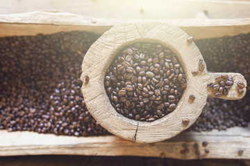 Coffee beans in a wooden vintage storage on coffee bean pile background.