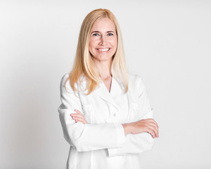 Happy middle-aged woman doctor in uniform crossing arms