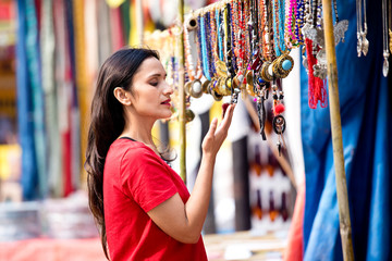 Two women shopping for necklace and earrings at street market
