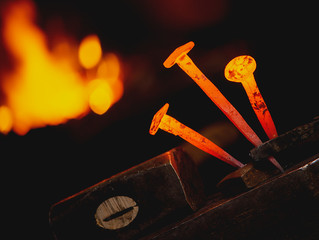 Close-up hot metal nail for horseshoes on an anvil in blacksmith's workshop