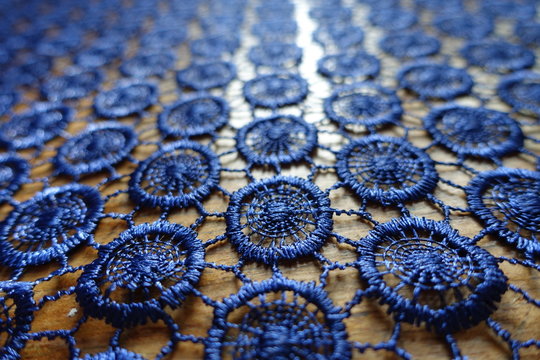 Closeup of dark blue crochet lacy fabric on wood