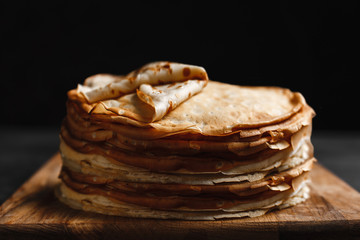 Maslenitsa Maslenitsa week is a holiday of food. A stack of Russian pancakes on a dark rustic wooden background. Front view with copy space