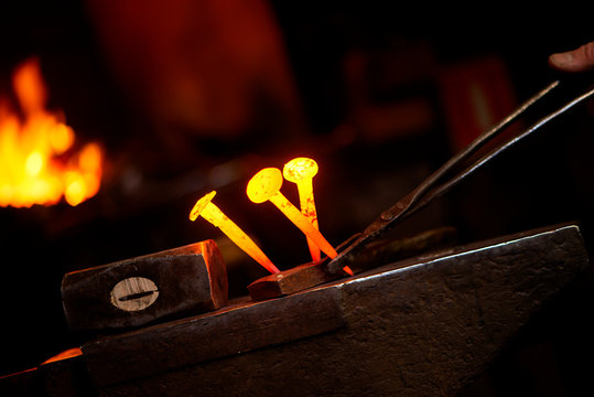 Close-up hot metal nail on an anvil in blacksmith's workshop