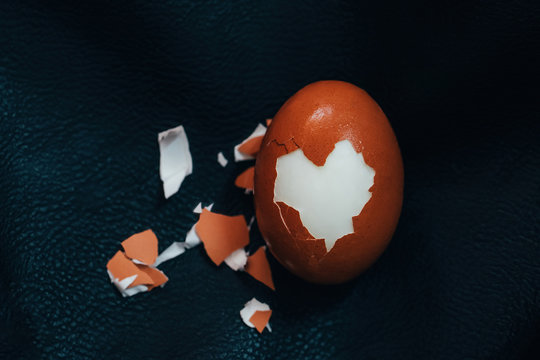 Cracked Hard Boiled Brown Egg With Heart Shaped Shell On Black Leather Background. Minimal Easter Holiday Concept.