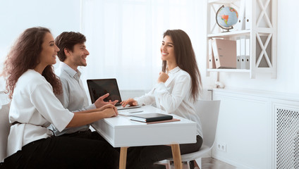 Young travel agent working with clients and discussing tour