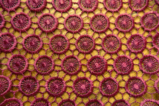 Dark red crochet lacy fabric on wood from above