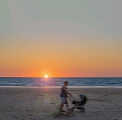 silhouette of a woman with stroller on the beach at sunset, Broome western Australia