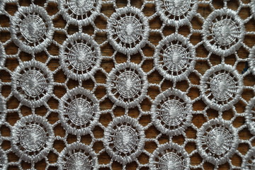 Close shot of ivory white crochet lacy fabric on wood from above