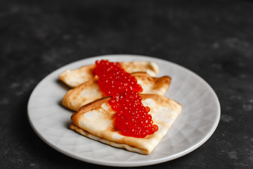 Maslenitsa Maslenitsa week is a holiday of food. Pancakes with red caviar on a plate with Cutlery. The view from the top. side view. space for text