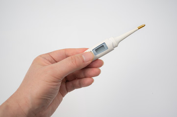 A male hand holding a digital thermometer in hand on a white background