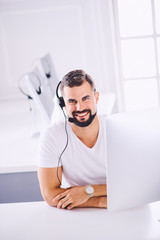 Young smiling customer support operator with hands-free headset working in the office. Concept