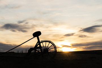 Silhouette Old Haymaking Machine (tractor) on grass field sunset time