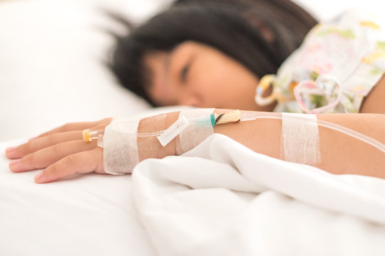 Asian Kid Patient Child Girl Inpatient Sad Look At IV Infusion Drop For On Hospital Bed. Cancer Chemotherapy Chemo Medical Healthcare Concept