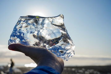 traveler hand holding crystal ice piece at diamond beach Iceland 