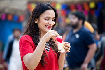 One women eating flavored ice gola dipped in syrup