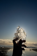 Silhouette crystal ice piece break holding by hand in afternoon time Diamond beach Jokulsarlon, Iceland
