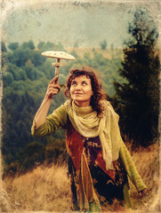 Woman with mushroom, on mountain meadow, mushroom as a umbrella, old photo effect.