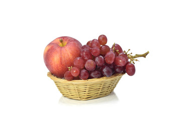 Red grapes and apple in bamboo basket isolate on white background.
