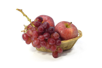 Red grapes and apple in bamboo basket isolate on white background