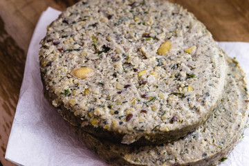vegan hamburger based on various vegetables, raw, without frying, on wooden background.Vegan food and healthy living concept.