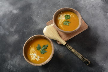 Sweet potato and carrot soup served with sour cream in wooden bowl. Orange vegetable soup concept. Vegan food