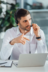 handsome male translator working online with headset and laptop