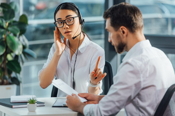 professional asian translator working online with headset while having meeting with businessman