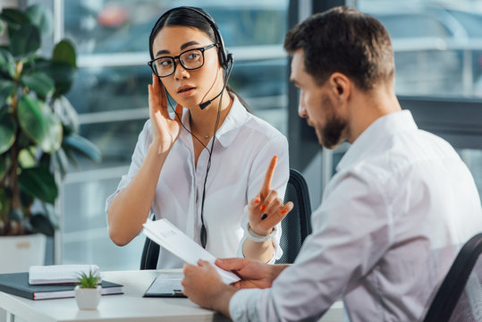 Professional Asian Translator Working Online With Headset While Having Meeting With Businessman