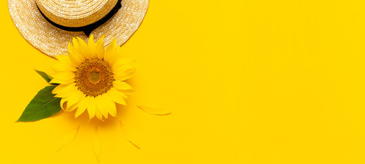 Beautiful fresh sunflowers, straw hat on bright yellow background. Flat lay top view copy space....