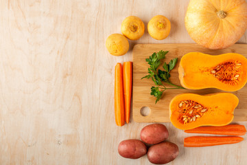 sliced pumpkin and carrots and whole vegetables on a cutting Board and a wooden background