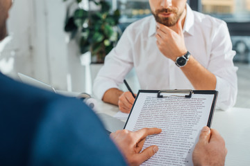 cropped view of translator working with businessman and documents in modern office