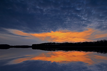 Landscape of a spring sunset at Crooked Lake, with reflections in calm water, Michigan, USA