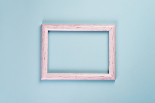 Blank old wooden frame for photos or different pictures on a pastel blue background.