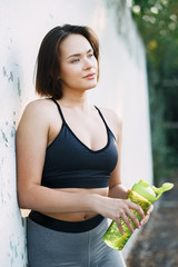Obraz premium a young attractive girl in sportswear on the Playground holding a sports water bottle in the summer