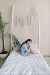 Close-up portrait of a young beautiful woman with dark hair. Young brunette in the bedroom at home. Good morning. Lifestyle.