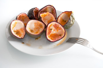  On a table a white plate with eaten passion fruit. 